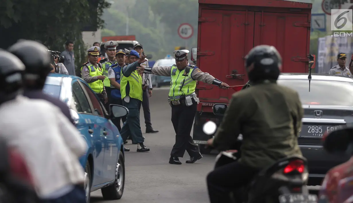 Petugas polisi lalu lintas memberhentikan kendaraan saat pemberlakuan sistem ganjil genap di pintu masuk Gardu Tol Cibubur 2, Jakarta, Senin (16/4). Kebijakan ini diterapkan untuk mengurai kemacetan di ruas Tol Jagorawi. (Liputan6.com/Faizal Fanani)