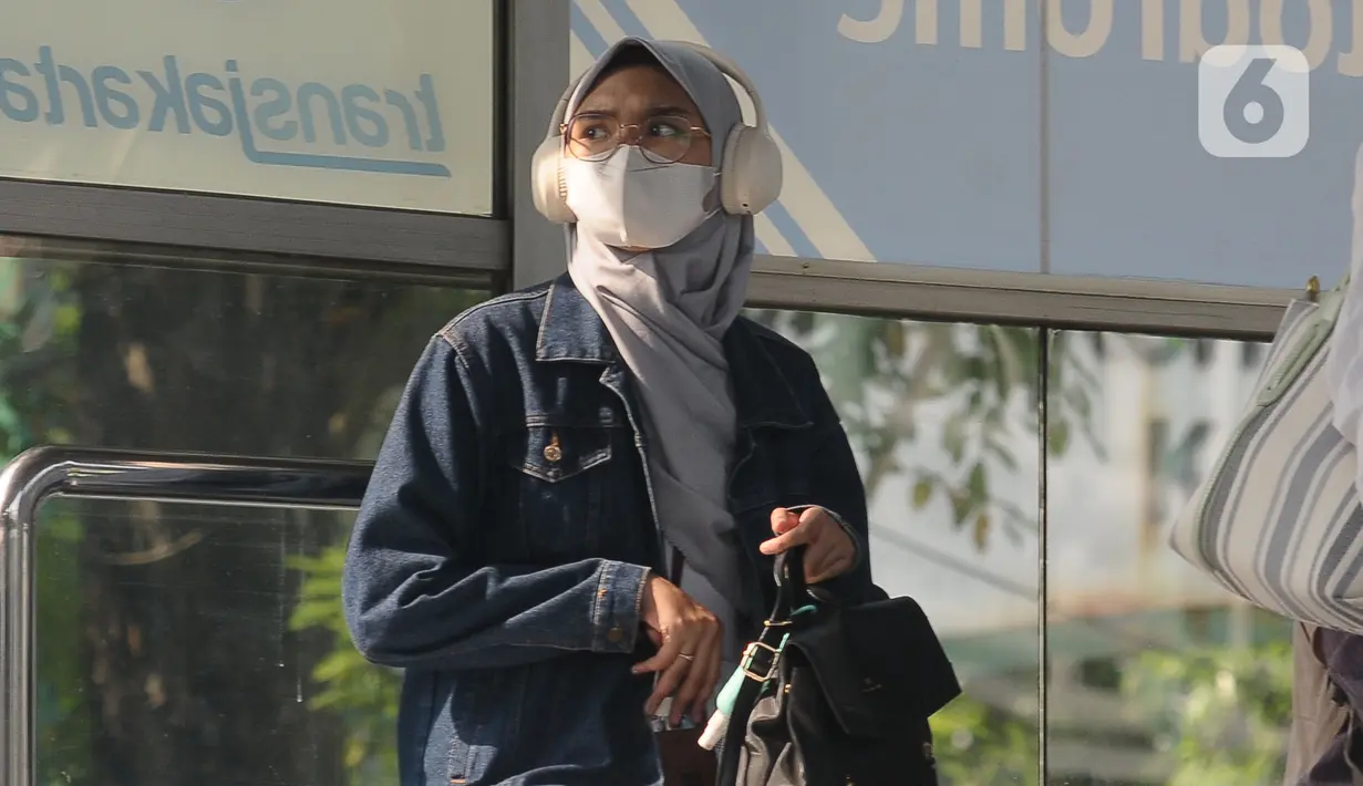 Seorang wanita mengenakan masker berada di halte Transjakarta di Kawasan Velodrome Jakarta Timur, Jumat (28/7/2023). (merdeka.com/imam buhori)