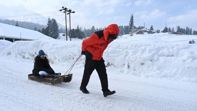 Seorang pria menarik seorang anak di atas kereta luncur di resor ski di Gulmarg, sekitar 55 km utara Srinagar, Jammu dan Kashmir, India, 25 Januari 2021. Sebagian besar orang India akan menetapkan Gulmarg sebagai destinasi liburan musim dingin favorit mereka. (Tauseef MUSTAFA/AFP)