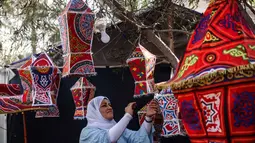 Fanous merupakan lentera tradisional berwarna-warni yang digunakan sebagai dekorasi khas untuk merayakan bulan suci Ramadan. Tampak dalam foto, Rehan Hazem Sharab, seorang warga Palestina berusia 32 tahun, membuat lampion buatan tangan dari kotak-kotak bantuan yang tersisa sebagai persiapan menyambut bulan suci Ramadan yang dimulai pada 17 Februari, di luar tendanya di lingkungan Al-Mawasi, Khan Younis, di Jalur Gaza selatan pada Sabtu 7 Februari 2026. (Bashar Taleb/AFP)