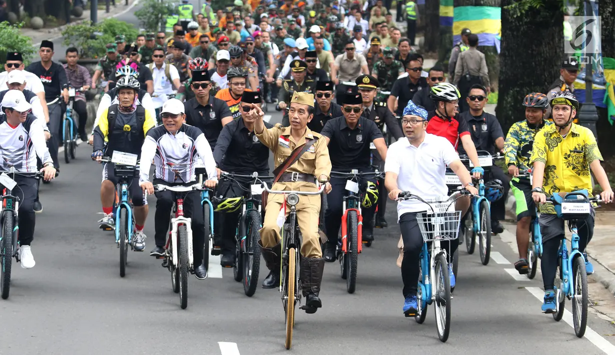 Presiden Joko Widodo atau Jokowi (tengah) didampingi Gubernur Jawa Barat Ridwan Kamil (kanan) saat mengikuti Bandung Lautan Sepeda, Sabtu (10/11). Kegiatan ini diikuti oleh anggota TNI dan Polri serta masyarakat Kota Bandung. (Liputan6.com/Angga Yuniar)