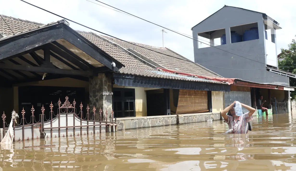 Warga melintasi banjir yang merendam perumahan Ciledug Indah, Tangerang, Banten, Kamis (2/1/2020). Memasuki hari kedua, kondisi perumahan tersebut masih tergenang banjir setinggi dada orang dewasa. (Liputan6.com/Angga Yuniar)