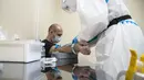 Petugas medis mengambil sampel darah dari seorang pasien di rumah sakit sementara virus corona COVID-19 di Istana Es Krylatskoe di Moskow, Rusia, Rabu (18/11/2020). Otoritas Moskow mengubah arena seluncur es menjadi rumah sakit sementara untuk menangani pasien COVID-19. (AP/Pavel Golovkin)