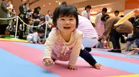 Seorang bayi tersenyum dan ingin menghampiri ibunya saat kompetisi 'Bayi Merangkak',  Yokohama, Jepang, Senin (23/11/2015). Tingkah bayi yang lucu menjadi pemandangan yang menggemaskan bagi para penonton. (AFP Photo/Kazuhiro Nogi)