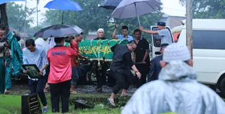 Jenazah aktor senior Deddy Sutomo saat diturunkan dari mobil ambulan. Siang itu, disekitar Tempat Pemakaman Umum Tanah Kusir, Jakarta Selatan sedang di guyur hujan. (Adrian Putra/Bintang.com)
