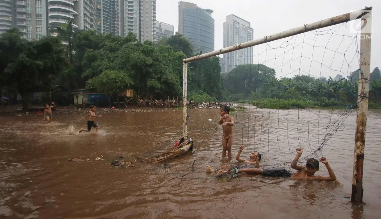 Anak-anak bermain di lapangan sepak bola di kawasan Kemang, Jakarta, Kamis (16/11). Tingginya intensitas hujan dan pesatnya pembangunan menyebabkan kawasan tersebut langganan banjir yang berasal dari luapan Kali Krukut. (Liputan6.com/Immanuel Antonius)