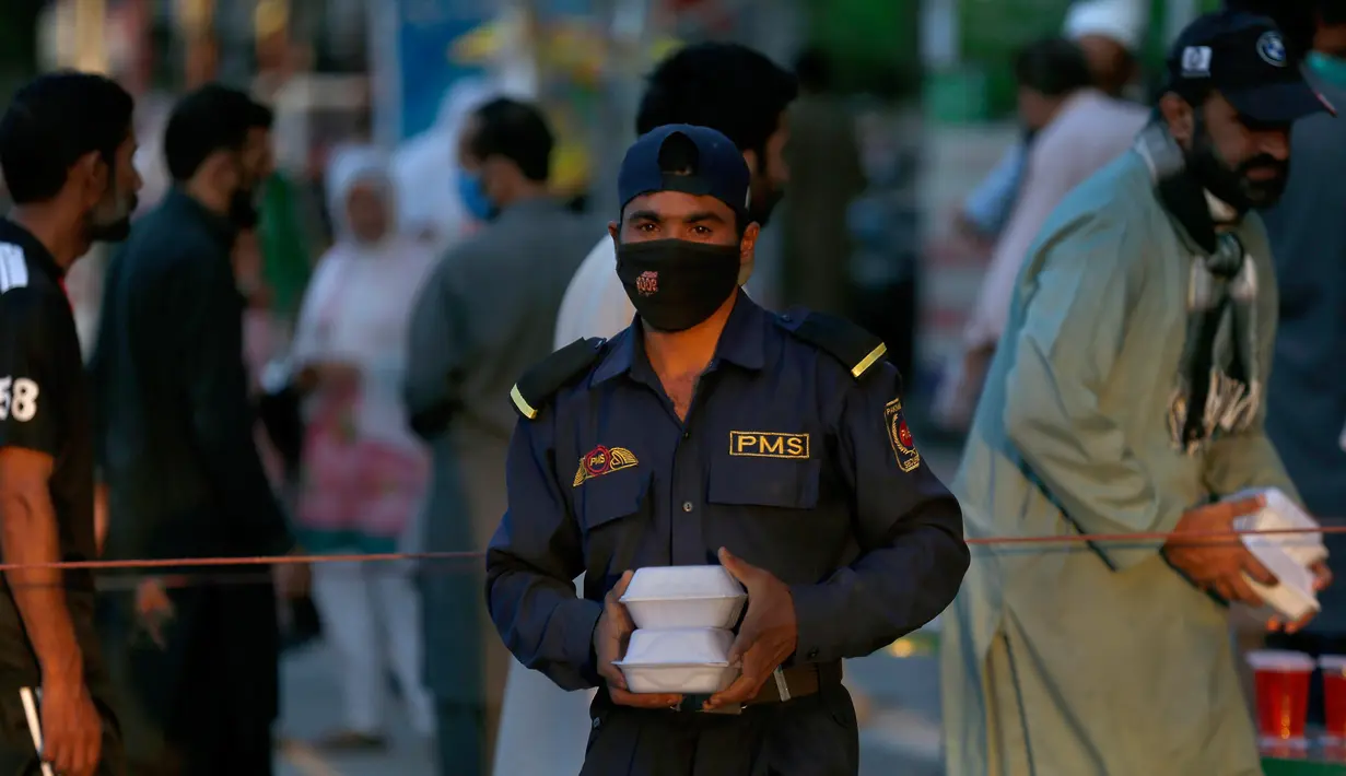 Seorang pria menerima kotak makanan dan minuman manis tradisional untuk berbuka puasa di Rawalpindi, Pakistan, Minggu, (3/5/2020). Umat Muslim di seluruh dunia sedang melaksanakan Ramadan untuk menahan diri dari makan, minum sejak subuh sampai senja. (AP/Anjum Naveed)