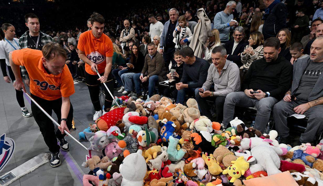 Sejumlah petugas mengumpulkan sejumlah boneka dilemparkan oleh para penonton sebelum laga lanjutan Euroleague Basketball 2024/2025 antara Partizan Belgrade melawan Maccabi Tel Aviv di Belgrade, Serbia, Jumat (03/01/2025) waktu setempat. (AFP/Oliver Bunic)