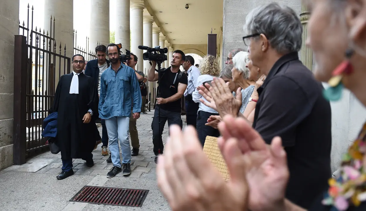 Petani Prancis, Cedric Herrou didampingi pengacaranya berjalan meninggalkan gedung pengadilan di Aix-en-Provence, Selasa (8/8). Pengadilan mendakwa Cedric Herrou dengan tuduhan membantu imigran gelap masuk dan bermukim di Prancis. (boris HORVAT/AFP)