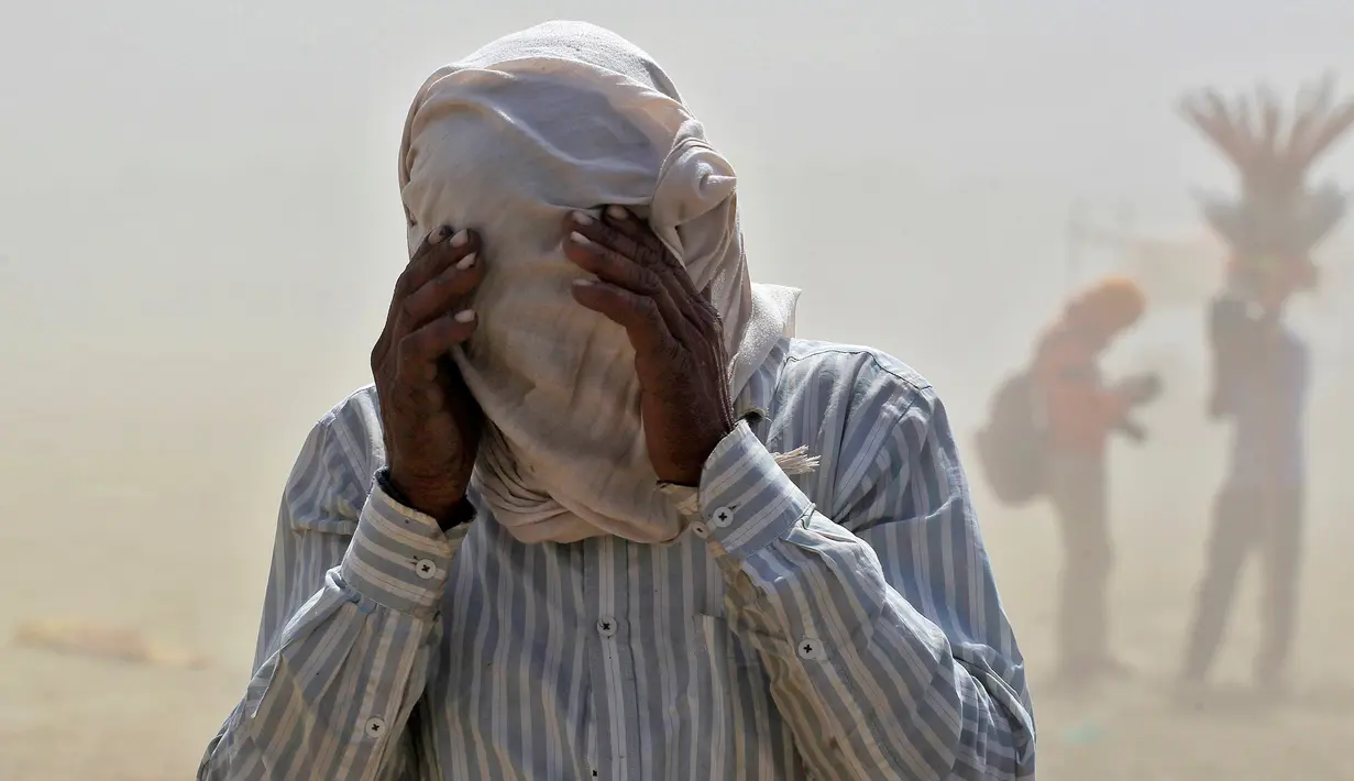 Seorang pria menutupi wajahnya dengan kain saat ia berjalan melintasi badai pasir di tepi sungai Gangga di Allahabad, India, Selasa (12/4/2016).  (REUTERS/Jitendra Prakash)