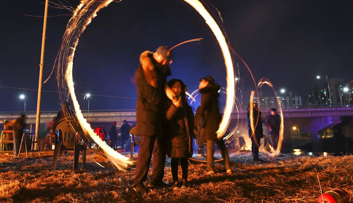 Warga Korea Selatan memutar kaleng arang yang terbakar selama perayaan  Bulan Purnama pertama tahun baru Imlek di Seoul (17/2). Permainan ini dipercaya dapat menyuburkan tanah dan menyingkirkannya hama. (AFP Photo/Jung Yeon-je)