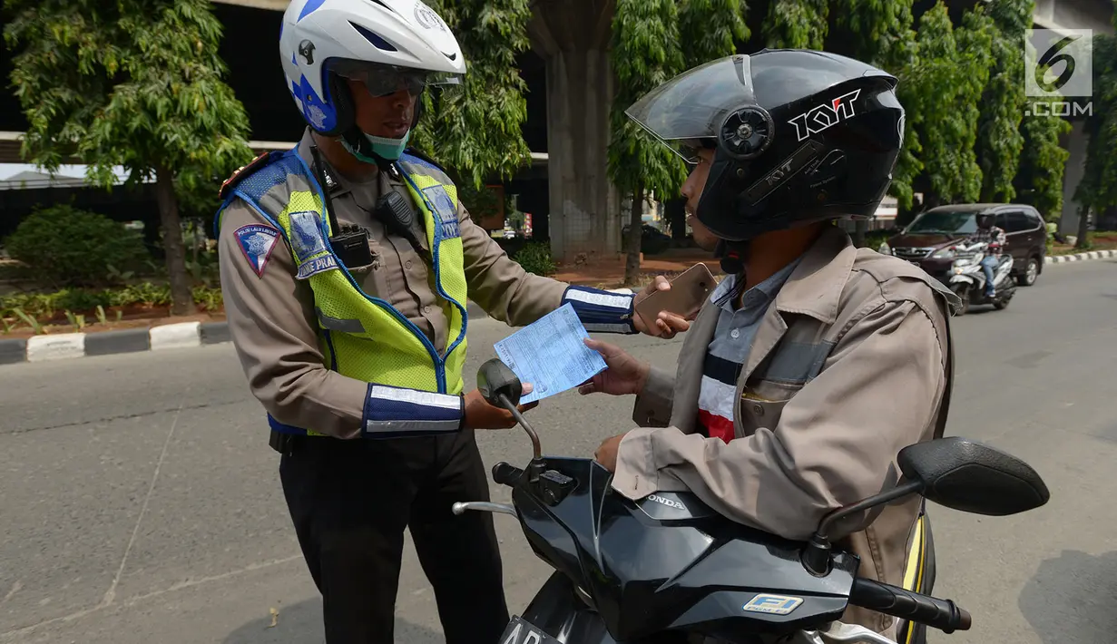 Polisi lalu lintas melakukan tilang terhadap pengendara motor saat razia Operasi Patuh Jaya 2019 di kawasan Kebon Nanas, Jakarta, Kamis (29/8/2019). Operasi ini diharapkan dapat meningkatkan kepatuhan dan ketertiban dalam berlalu lintas serta mengurangi angka kecelakaan. (merdeka.com/Imam Buhori)