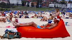Seorang turis pria berjemur saat merayakan hari Natal di Bondi Beach Sydney pada Hari Natal di Australia, (25/12). (REUTERS/David Gray)
