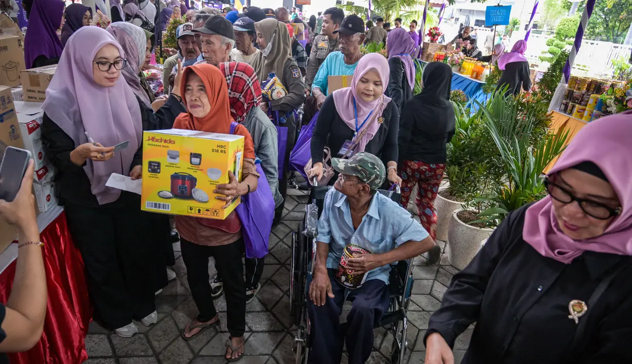 Tidak hanya bahan pangan, Gabungan Organisasi Wanita (GOW) juga memberikan barang-barang peralatan rumah, seperti panci, penggorengan, dan alat dapur lainnya. Tampak dalam foto, masyarakat menerima barang-barang gratis seperti pakaian, bahan makanan pokok, dan perlengkapan rumah tangga yang disediakan oleh Asosiasi Organisasi Wanita (GOW) dan pemerintah daerah selama kegiatan aksi sosial tahunan di bulan Ramadan, Surabaya pada Senin 2 Maret 2026. (JUNI KRISWANTO/AFP)