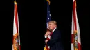 Capres AS dari Partai Republik, Donald Trump memeluk bendera AS saat melakukan kampanye menyapa pendukungnya di Tampa, Florida, AS (24/10). (REUTERS/Jonathan Ernst)