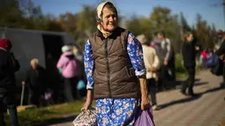 Seorang perempuan membawa tas berisi makanan yang diberikan oleh sukarelawan Ukraina di Izium, Ukraina, Rabu, 12 Oktober 2022. Situasi di Izium, dan pemukiman lain yang dibebaskan di dekatnya, sangat buruk. (AP Photo/Francisco Seco)