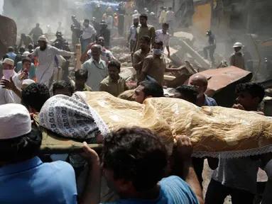 Warga mengevakuasi jenazah korban runtuhnya bangunan di Mumbai, India (31/8). Bangunan tua berlantai lima itu ambruk setelah dua hari kota Mumbai diguyur hujan lebat. (AP Photo / Rafiq Maqbool)