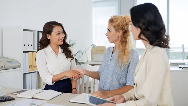 Tiga orang perempuan sedang berdiskusi di kantor dengan dua di antaranya sedang berjabat tangan (Foto Dok: Freepik/pressfoto)