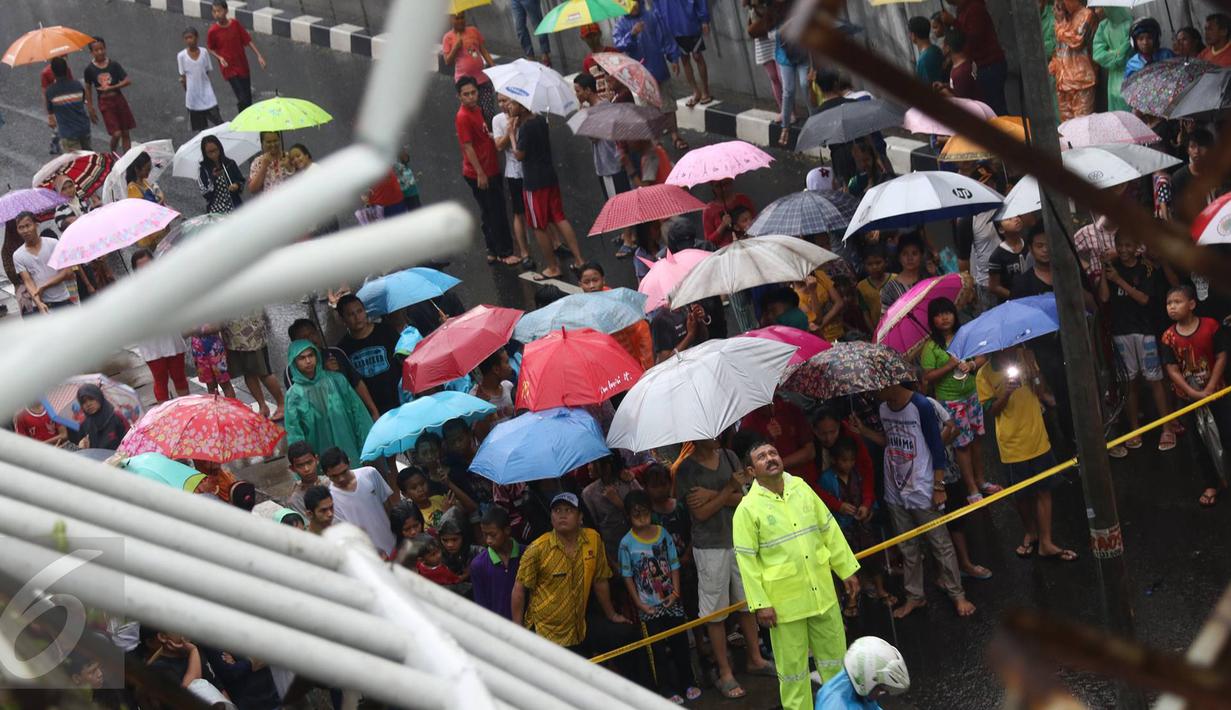 Warga menonton JPO yang roboh akibat hujan deras dan angin kencang di Jalan Raya Pasar Minggu, Jakarta Selatan, Sabtu (24/09). Keberadaan papan iklan dituding menjadi penyebab ambruknya JPO. (Liputan6.com/Immanuel Antonius)