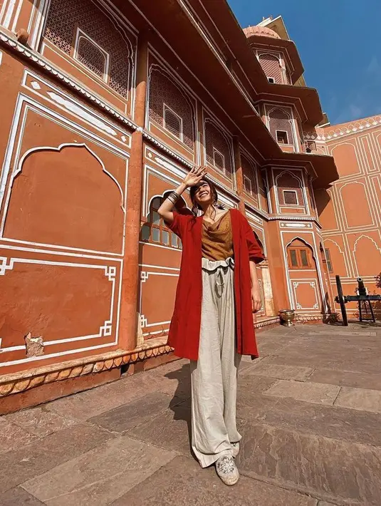 Padu padan silk tank top warna turmeric dengan cardigan warna merah dan wide leg pants warna cream juga tak kalah menarik. (Instagram/febbyrastanty).