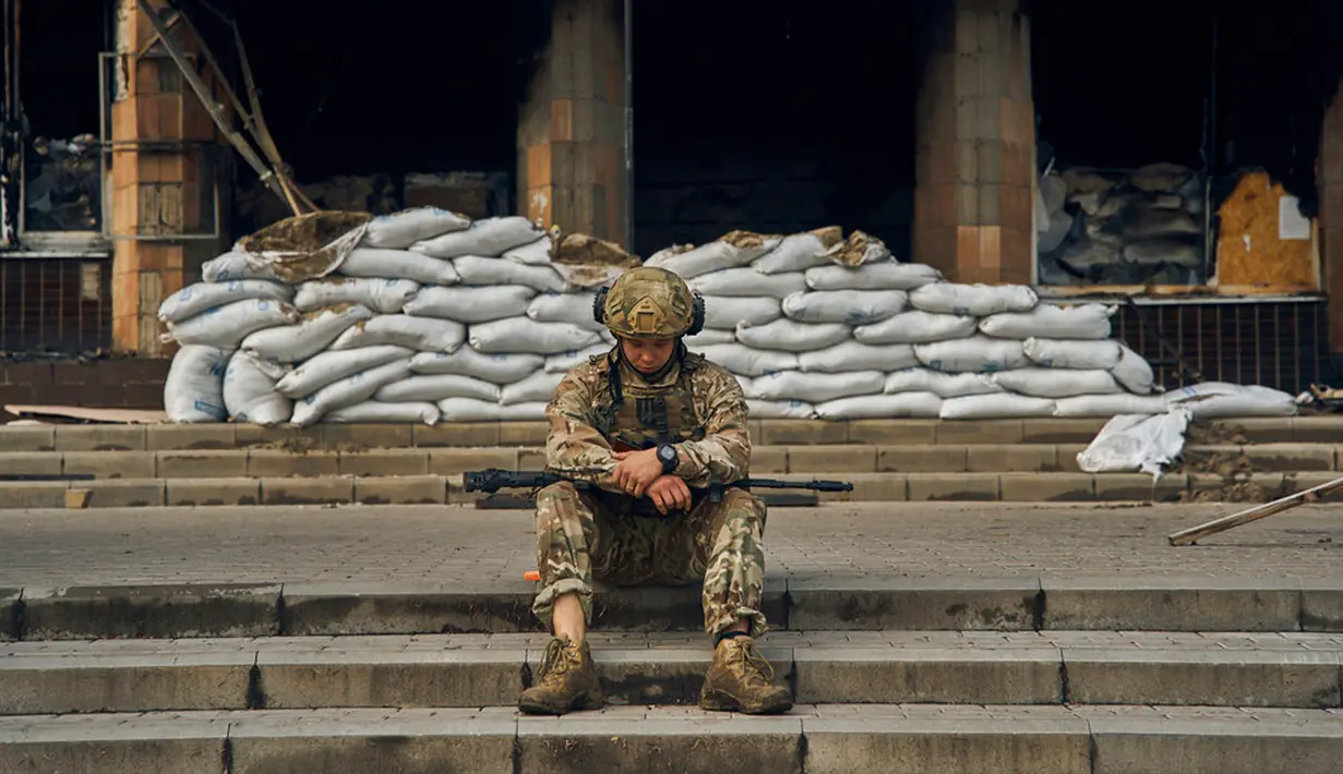 Seorang tentara Ukraina beristirahat di tangga Balai Kota di Izium, wilayah Kharkiv, Ukraina, 13 September 2022. Pasukan Ukraina juga berhasil membebaskan lebih dari 40 permukiman di Kharkiv. (AP Photo/Kostiantyn Liberov)
