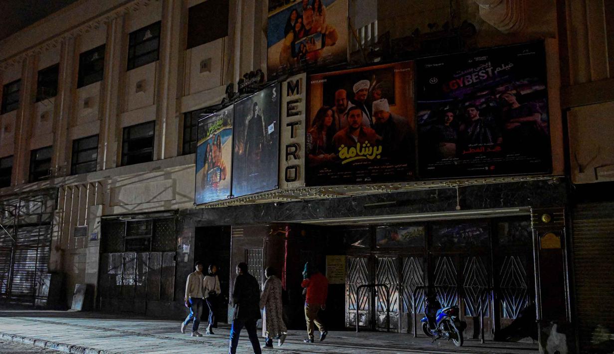 Sejumlah sektor bisnis seperti toko, restoran, pusat perbelanjaan, hingga kafe di Mesir dibatasi jam operasionalnya hanya sampai pukul 21.00 waktu setempat. Tampak dalam foto, orang-orang berjalan melewati bioskop yang tutup saat toko-toko tutup lebih awal di bawah jam malam yang diperintahkan pemerintah untuk mengurangi biaya energi di pusat kota Kairo, Mesir, pada Kamis 2 April 2026. (Khaled DESOUKI/AFP)