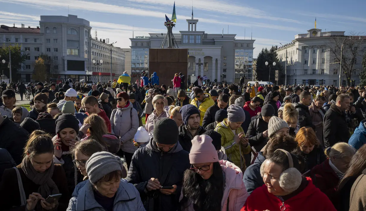Warga berkumpul di sebelah hotspot internet di Kherson, Ukraina selatan, Senin (14/11/2022). Penduduk Kota Kherson dengan gembira menyambut pasukan Ukraina, setelah Rusia mengatakan telah menarik diri sepenuhnya dari kota di selatan itu. (AP Photo/Bernat Armangue)