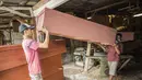 Para pekerja memindahkan peti mati saat pembuatan di sebuah bengkel di Surabaya, Jawa Timur, Senin (25/1/2021). Jumlah kematian akibat COVID-19 di Indonesia meningkat lebih dari 28.000. (Juni Kriswanto/AFP)