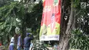 Petugas Satpol PP bersama Panwaslu kecamatan Ciracas menurunkan APK yang terpasang di salah satu pohon besar di Jalan Raya Bogor, Jakarta, Rabu (23/1). Penurunan APK ini karena pemasangannya dianggap melanggar ketentuan. (Liputan6.com/Helmi Fithriansyah)