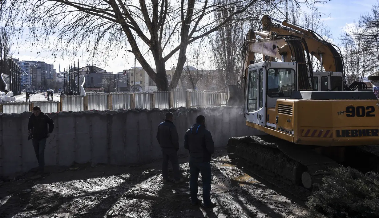 Kendaraan alat berat meruntuhkan tembok kontroversial di Mitrovica, Kosovo, Minggu (5/2). Tembok tersebut telah memicu ketegangan antara Kosovo dan negara tetangga Serbia. (AFP PHOTO/ ARMEND NIMANI)