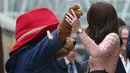 Kate Middleton berdansa dengan seorang aktor yang mengenakan kostum Paddington di stasiun kereta Paddington, London, Senin (16/10). Kate berdansa dalam iringan band yang memainkan lagu soundtrack untuk film kedua Paddington. (Jonathan Brady/Pool via AP)