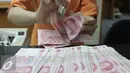 Seorang teller menghitung mata uang Yuan di Jakarta, Senin (30/11). Dana Moneter Internasional (IMF), Senin (30/11), resmi memasukan yuan, atau renminbi, ke dalam special drawing rights (SDR) sebagai mata uang elite dunia. (Liputan6.com/Angga Yuniar)