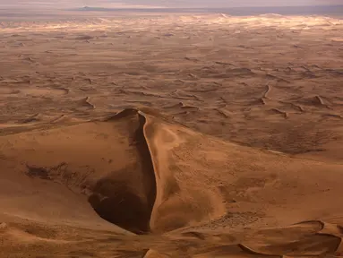 Pandangan dari udara sebuah bukit dikelilingi hamparan pasir Gurun Gobi wilayah Mongolia (21/7). Gurun terbesar di Asia ini sangat menakjubkan ketika dilihat dari udara. (AFP PHOTO / PATRICK BAZ)