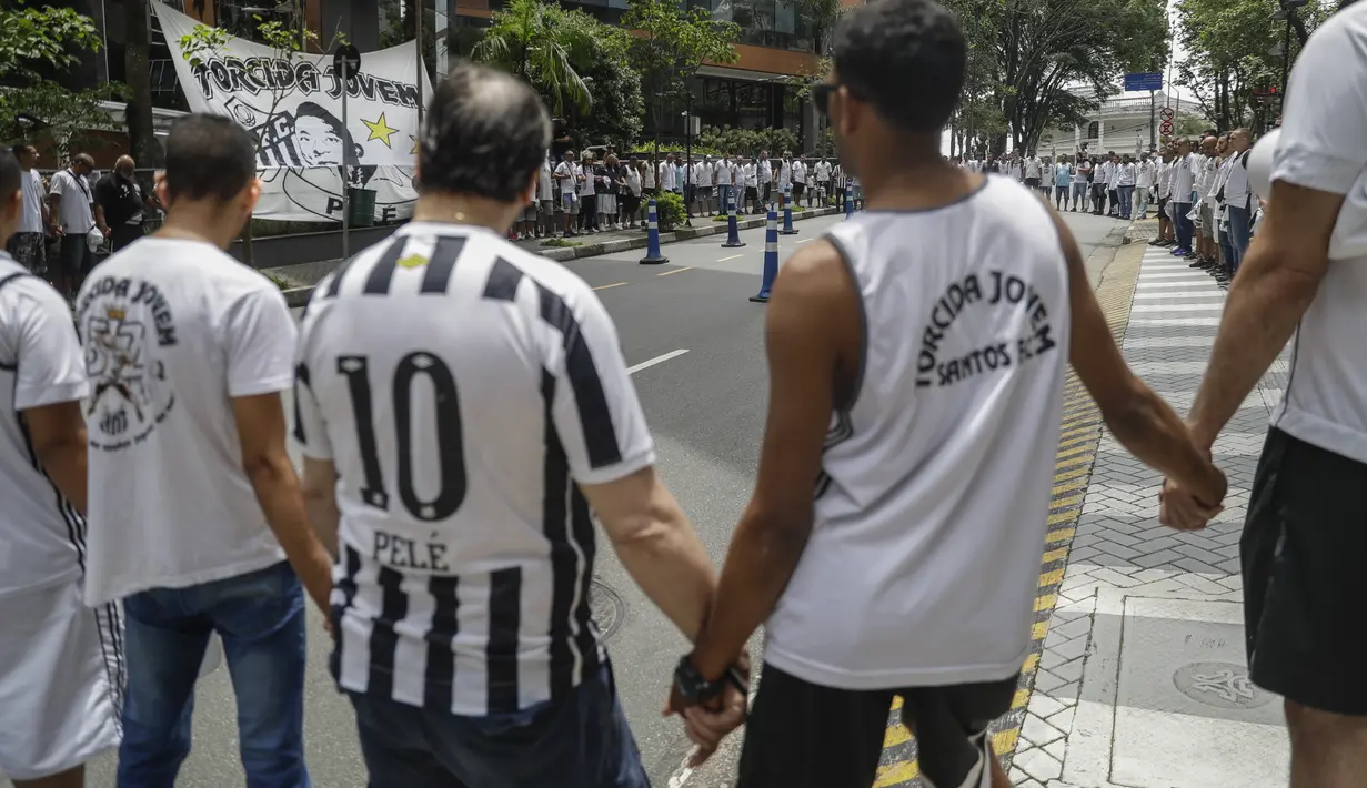 Pendukung tim sepak bola Santos berdoa untuk kesembuhan mantan bintang sepak bola Pele, di depan rumah sakit Albert Einstein di Sao Paulo, Minggu (4/12/2022). Pele disebut sedang menjalani penilaian ulang pengobatan kemoterapi. (AP Photo/Marcelo Chello)