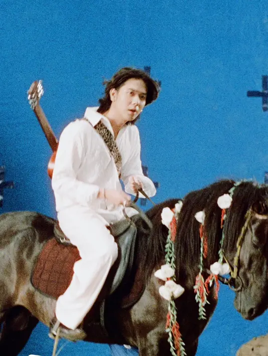 Dalam video klip 'Di Bawah Lampu', Iqbaal tampil seperti seorang pangeran berkuda. Ia tampil mengenakan pakaian serba putih sambil menggendong gitar. Aksinya yang menunggangi seekor kuda hitam pun menjadi sorotan. Bahkan, gayanya dimiripkan dengan Sang Raja Dangdut Rhoma Irama. (Liputan6.com/IG/@baale)