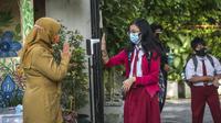 Seorang siswa menjalani pemeriksaan suhu tubuh saat memasuki sekolah sebelum mengikuti pembelajaran tatap muka (PTM) di sebuah sekolah di Surabaya, Jawa Timur, Senin (6/9/2021). Pemerintah kembali membuka sekolah di tengah pandemi COVID-19. (JUNI KRISWANTO/AFP)