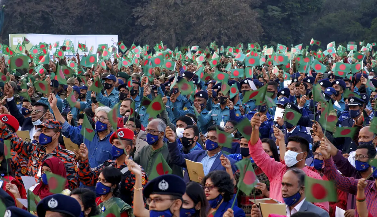 Para pejabat Bangladesh dan lainnya mengibarkan bendera nasional saat perayaan 50 tahun kemenangan atas Pakistan pada sebuah acara di Dhaka, Bangladesh, 16 Desember 2021. Pada 16 Desember 1971, tentara Pakistan menyerah kepada pasukan gabungan India-Bangladesh. (AP Photo/Mahmud Hossain Opu)