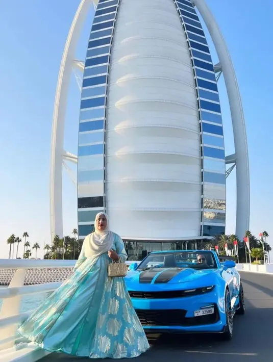 Bak crazy rich Dubai, Tasyi berpose di hotel bintang 7, Burj Al Arab dalam balutan abaya biru muda dengan detail motif keemasan, dilengkapi tas Prada galleria satin with crystal. @tasyiiathasyia.