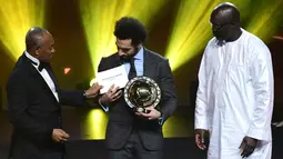 Presiden Konfederasi Sepak Bola Afrika (CAF) Ahmad Ahmad memberikan penghargaan Pemain Terbaik Afrika 2018 kepada bintang Liverpool, Mohamed Salah dalam malam penghargaan di Dakar, Senegal, Selasa (8/1). (SEYLLOU/AFP)