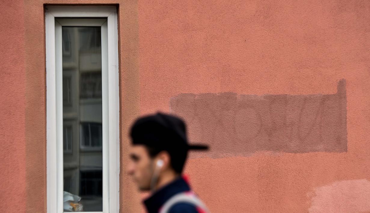 Seorang pria berjalan melewati sebuah tulisan bertuliskan "Pergi!" yang dicat dengan cat baru di dinding sebuah bangunan di Minsk (25/8/2020). Alexander Lukashenko mengklaim dirinya menang pada masa jabatan keenam dalam pemilihan yang disengketakan pada 9 Agustus. (AFP/Sergei Gapon)