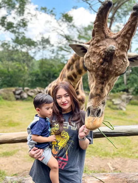 Seru menikmati pemandangan indah di Bogor, seleb yang saat ini menyandang status janda menikmati momen liburan ke Taman Safari. Di Taman Safari ini banyak menikmati momen bermain bersama binatang-binatang yang banyak disukai anak-anak seperti Jerapah. (Liputan6.com/IG/@nathalieholscher)