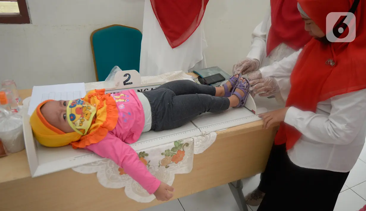 Bidan mengukur tinggi badan balita di Posyandu RW 20, Kelurahan Pondok Benda, Tangerang Selatan, Selasa (18/8/2020). Pemerintah sudah mengaktifkan pelayanan posyandu ke tiga sejak pandemi Covid-19 dengan memperketat protokol kesehatan. (merdeka.com/Dwi Narwoko)