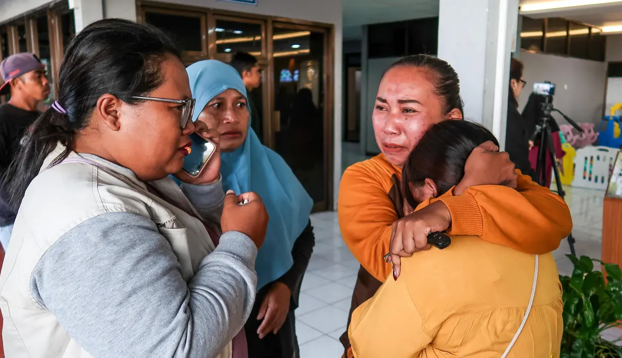 Anggota keluarga dan kerabat menunggu kabar terbaru tentang operasi pencarian sebuah kapal feri yang tenggelam di lepas pantai Bali, di Pelabuhan Ketapang, Banyuwangi, Jawa Timur, pada Kamis 3 Juli 2025. (Foto oleh AFP)