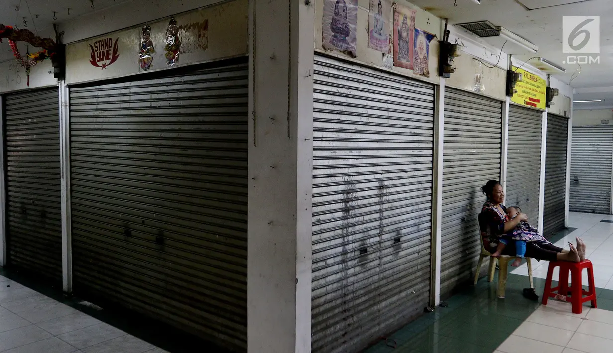 Seorang ibu menggendong anaknya di pertokoan elektronik Glodok, Jakarta, Minggu (17/6). Hampir 90 persen pertokoan di Glodok tutup pada Lebaran tahun ini. (Liputan6.com/JohanTallo)