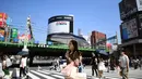 Seorang wanita menggunakan payung untuk melindungi dirinya dari sinar matahari selama gelombang panas saat melintasi jalan di distrik Shinjuku Tokyo, Minggu (4/8/2019). Setelah menyerang beberapa wilayah di Eropa, suhu tinggi juga terjadi di Jepang. (Charly TRIBALLEAU / AFP)