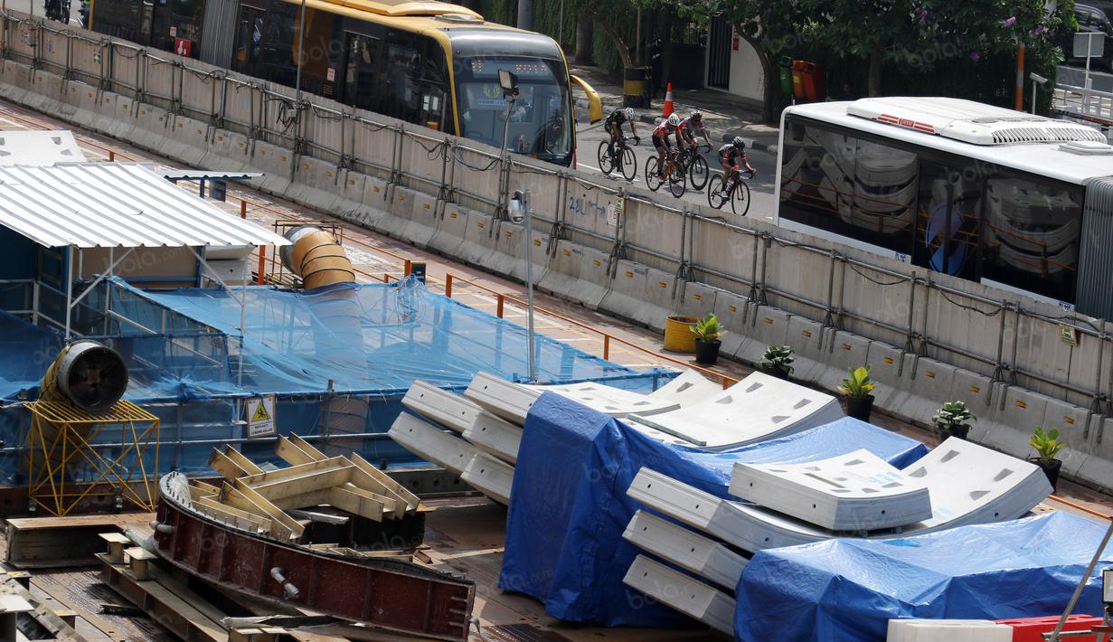 Para pebalap bersaing diantara Bus Trans Jakarta saat melewati ruas jalan protokol Sudirman pada ajang Tour de Jakarta di Bundaran Hotel Indonesia, Jakarta, Sabtu (30/7/2016). (Bola.com/Nicklas Hanoatubun)