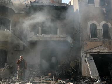 Seorang pria berdiri di depan puing-puing bangunan yang masih berasap di lokasi serangan udara Israel yang menargetkan sebuah lingkungan di Baalbeck di lembah Bekaa timur Lebanon pada 10 November 2024. (Nidal SOLH/AFP)