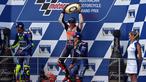 Pembalap Repsol Honda, Marc Marquez (tengah) mengangkat trofi usai keluar sebagai juara MotoGP Australia di Phillip Island (22/10). Dalam MotoGP Australia ini tempat kedua diisi Rossi dan ketiga menjadi milik Vinales. (AFP Photo/Paul Crock)