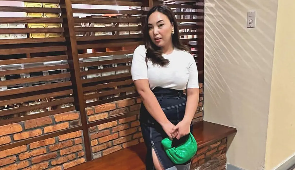 Angelica juga mengenakan skirt asimetris denim dengan atasan putihnya. Sambil membawa tas hijau.  [@angelicamanopo]