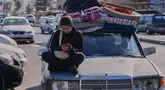 Seorang wanita pengungsi memeriksa ponselnya sambil menunggu untuk kembali ke desanya setelah pengumuman kesepakatan gencatan senjata awal antara Amerika Serikat dan Iran, di kota pelabuhan selatan Sidon, Lebanon, Senin 15 Juni 2026. (AP Photo/Mohammed Zaatari)